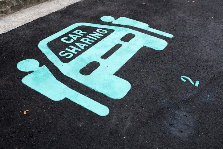 pictogram image on the street of a blue car with two people entering on either side, representing 'car sharing